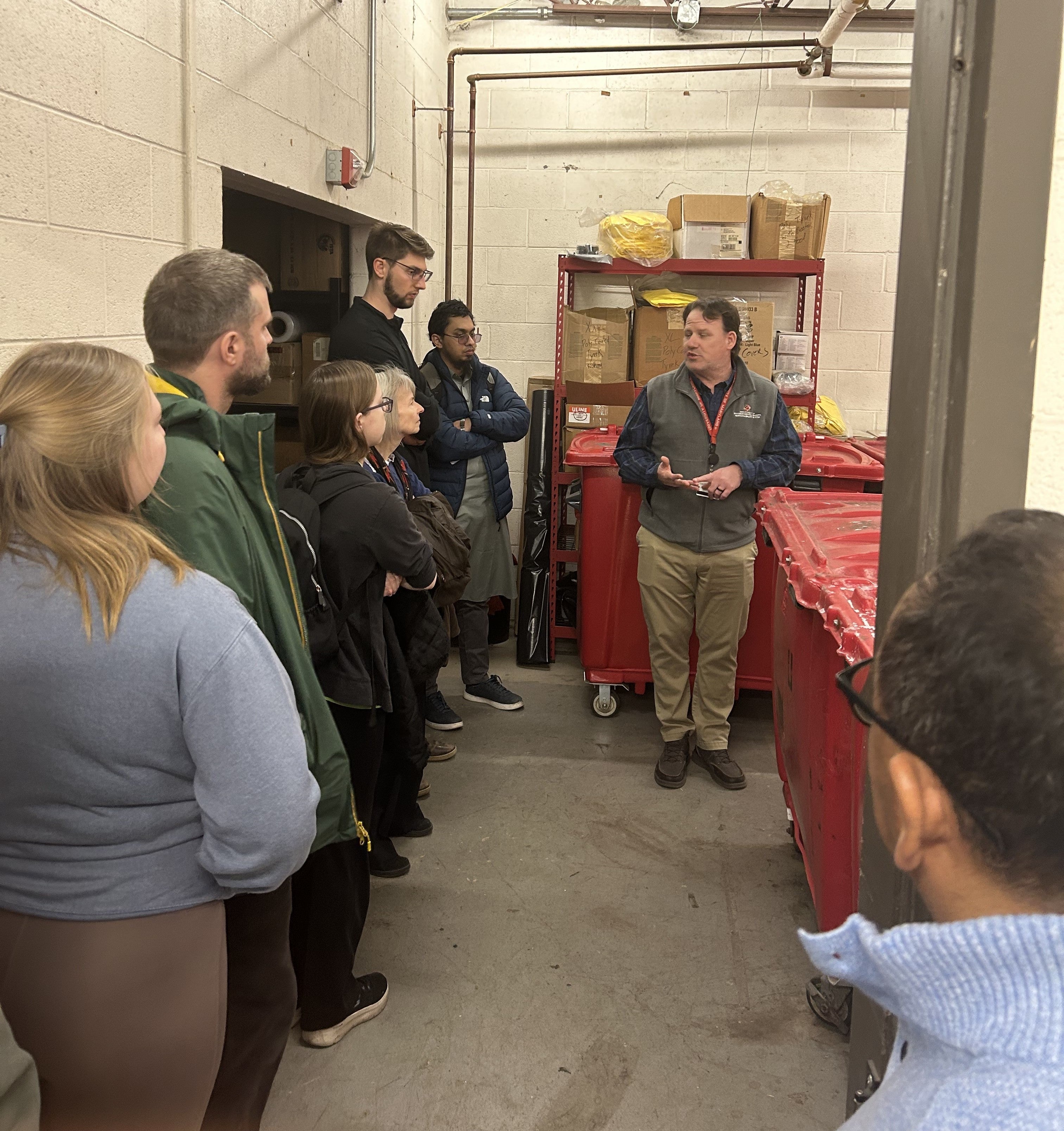 warehouse for storing hazardous waste shows several people learning about where chemicals and red bag waste go on campus