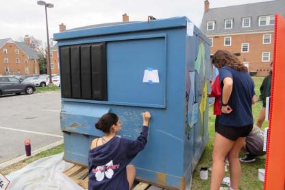 Students painting a dumpster