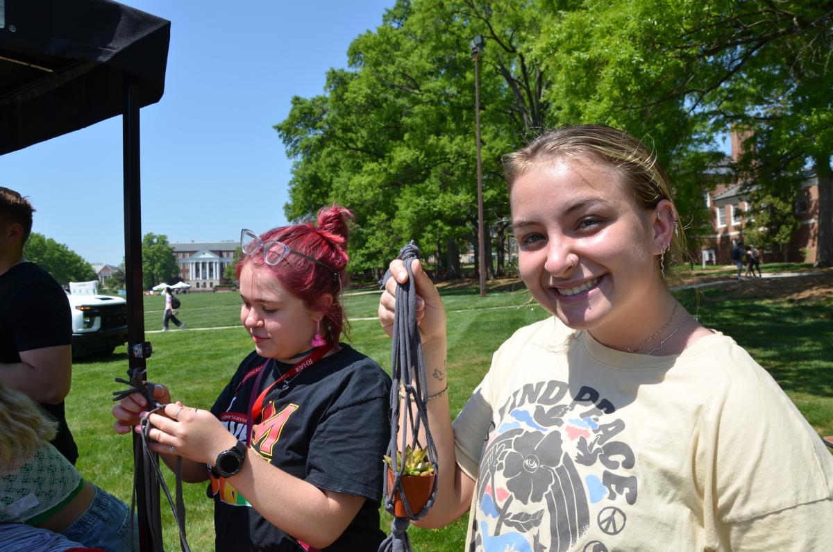 Student smiling while holding t-shirt macrome plant hanger