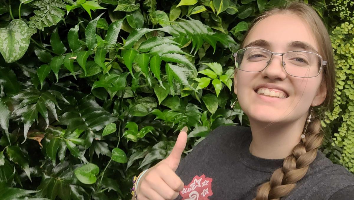 student posing in front of a biowall