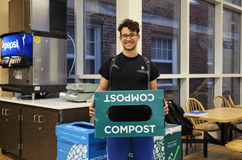 Student holding up compost bin lid in a Residence Hall