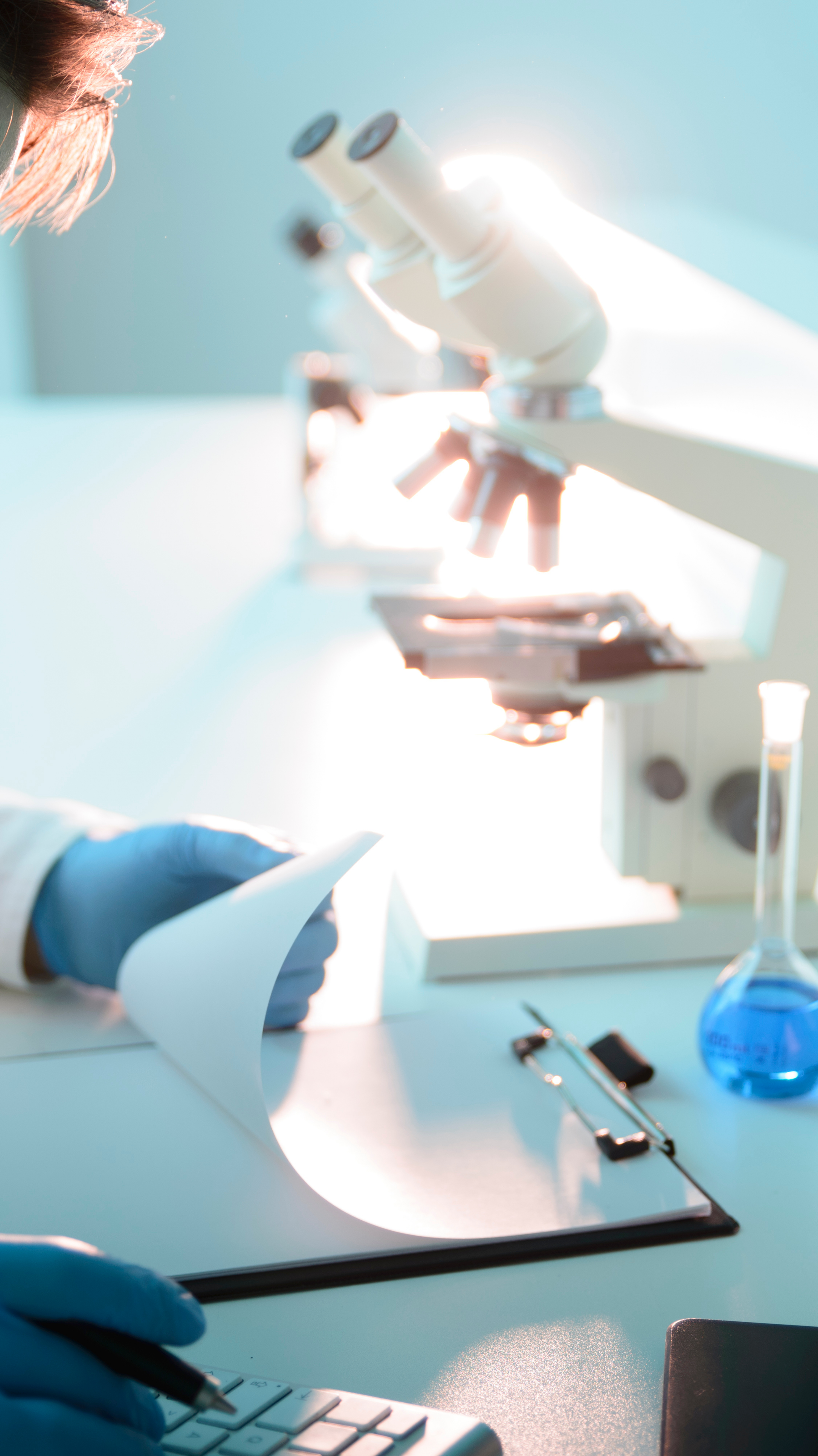 Photo of a person in a lap with a clipboard and microscope