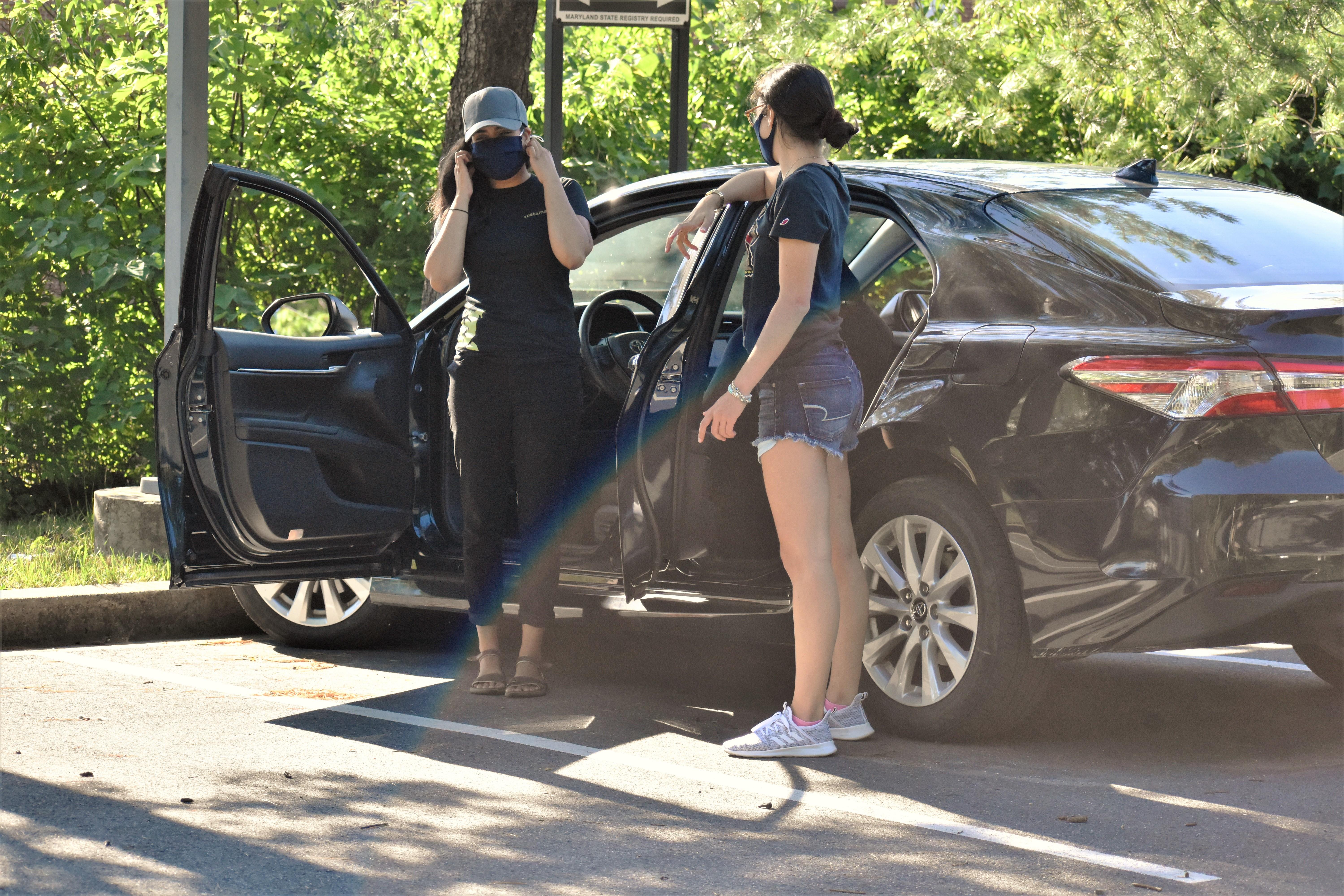 Two people standing next to a car on campus