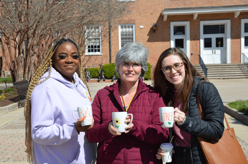 Staff holding decorating reusable mugs