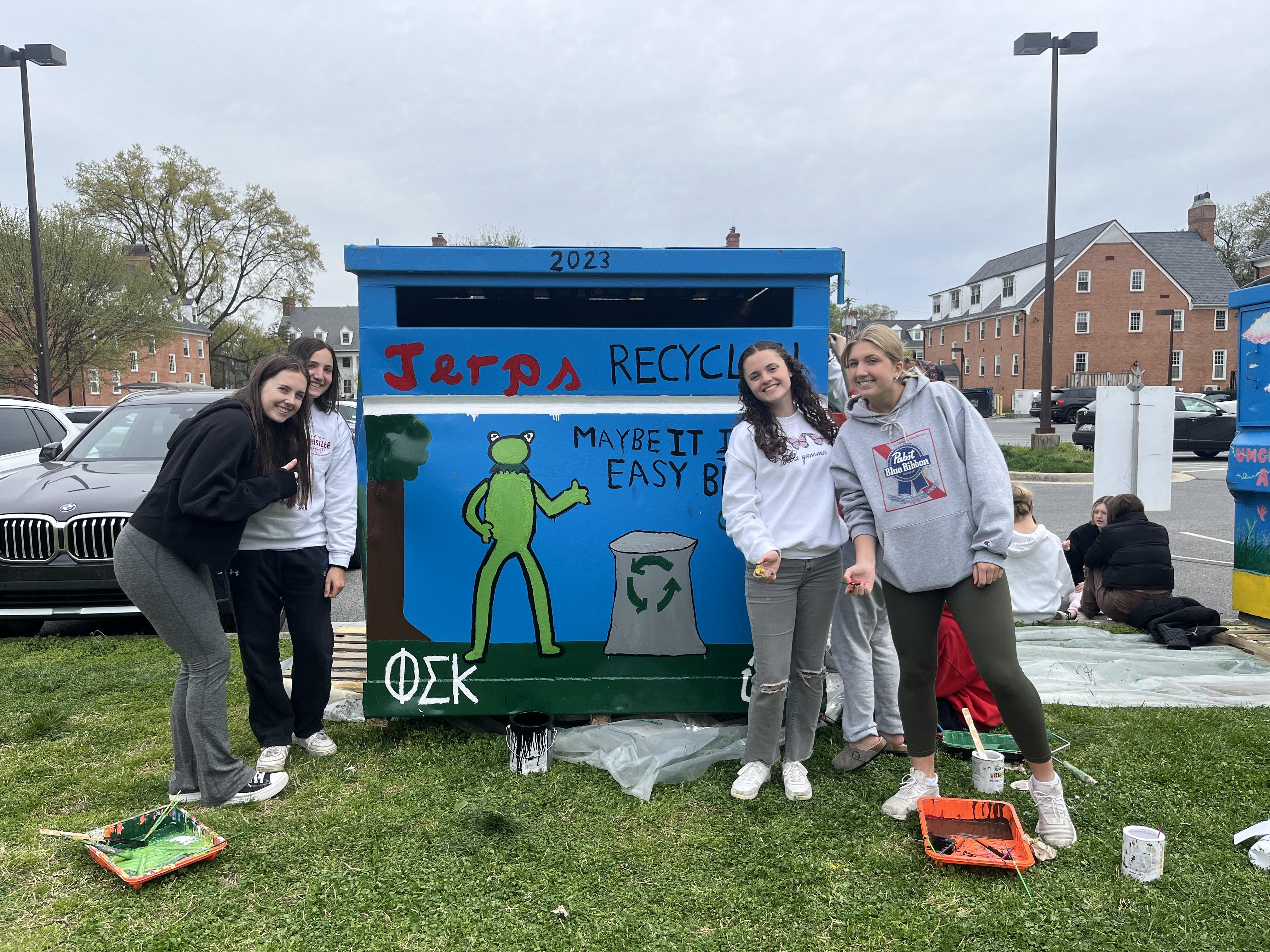 Students in front of decorated recycling dumpster