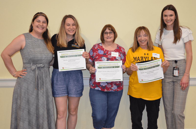 Five staff standing, three holding Green Workspace certificates