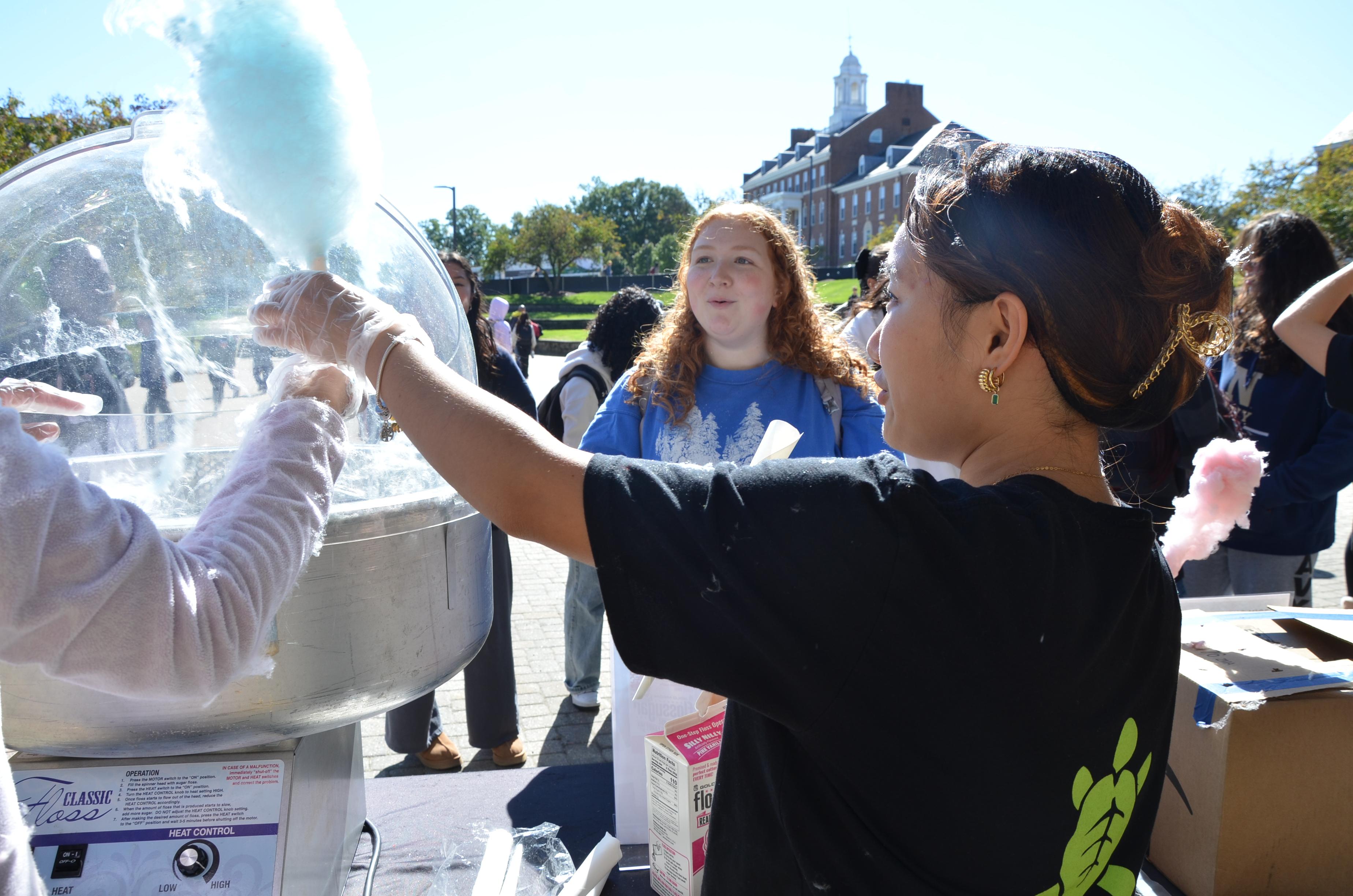 Image of an Office of Sustainability intern making blue cotton candy for a student