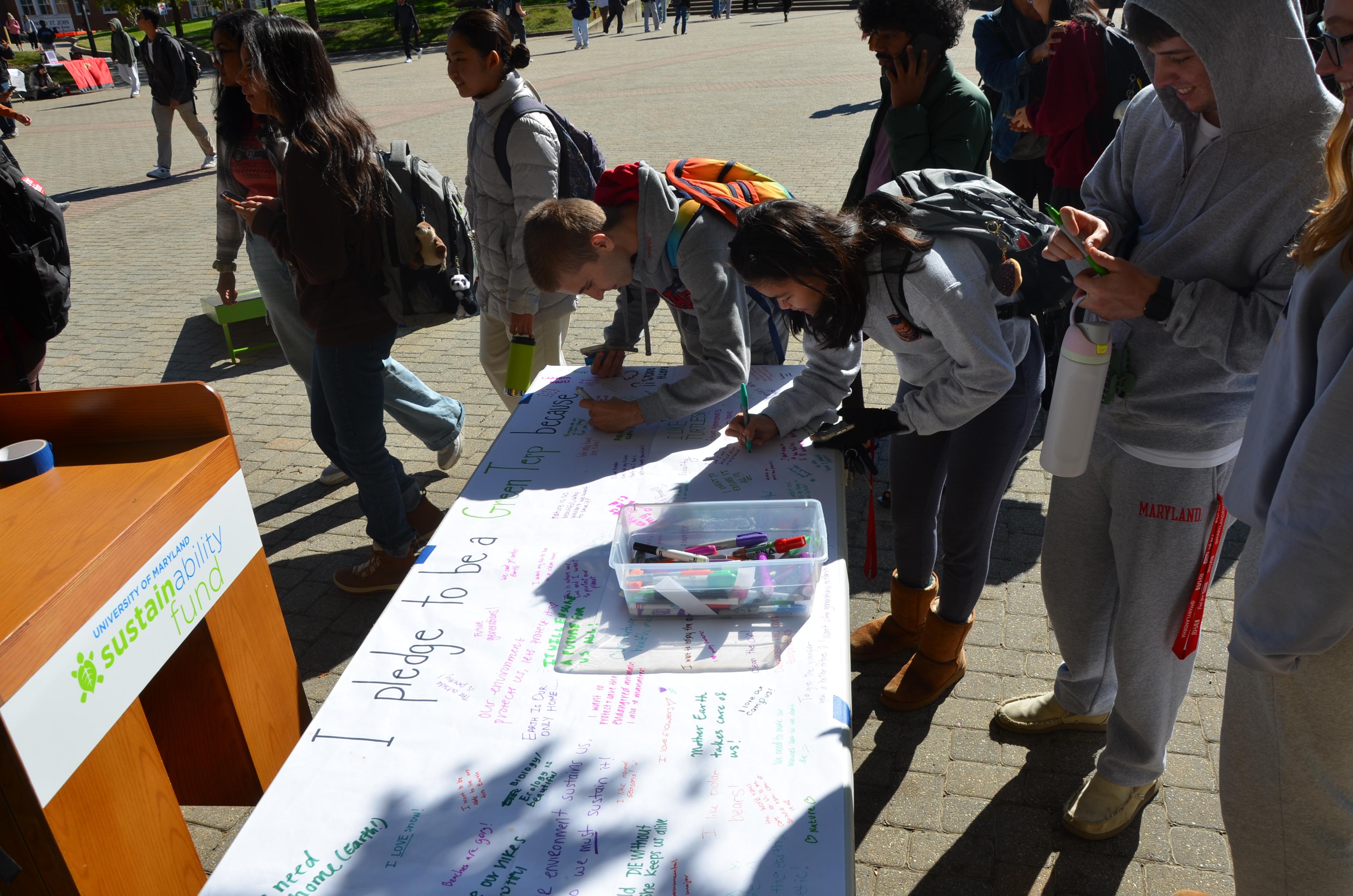 Image of two students writing a pledge as to how they will be a Green Terp