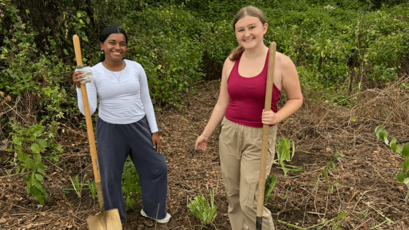 2 students holding shovels and planting plants