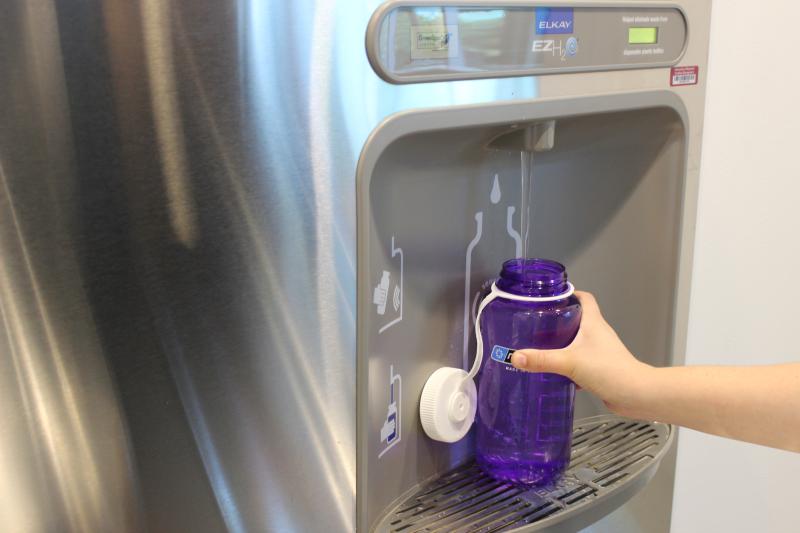 Someone filling up a water bottle at a filling station